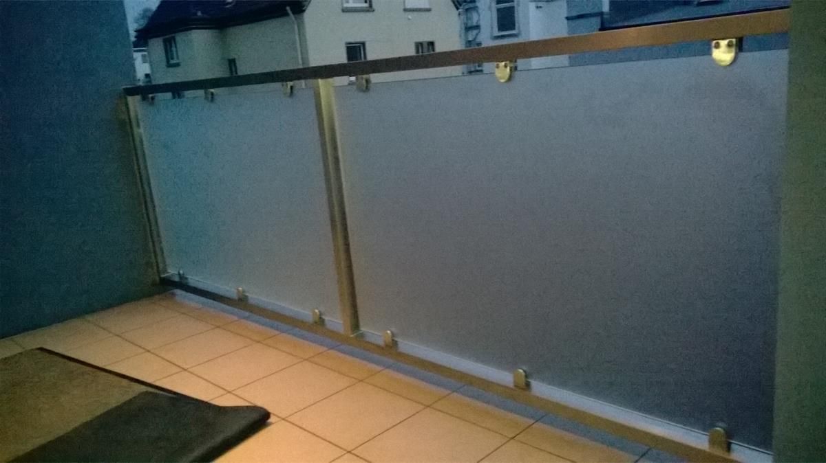 Ein Balkon mit Glasgeländer und einer Matte auf dem Boden