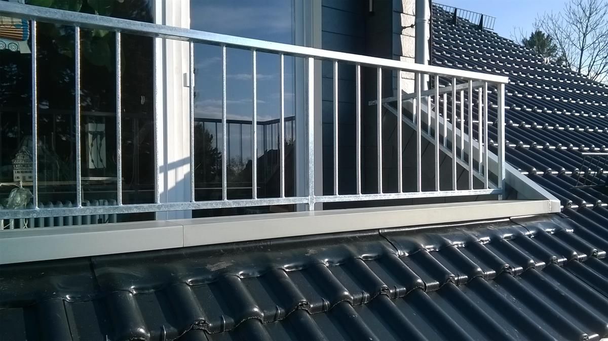 Ein Balkon mit Metallgeländer auf einem Ziegeldach