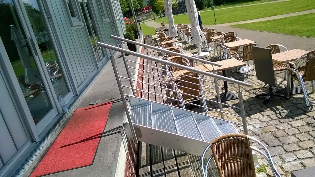 Eine Terrasse mit Tischen und Stühlen und einem roten Teppich