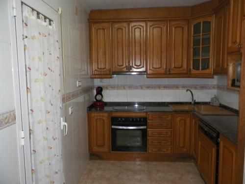 Una cocina con gabinetes de madera, una estufa y un fregadero.