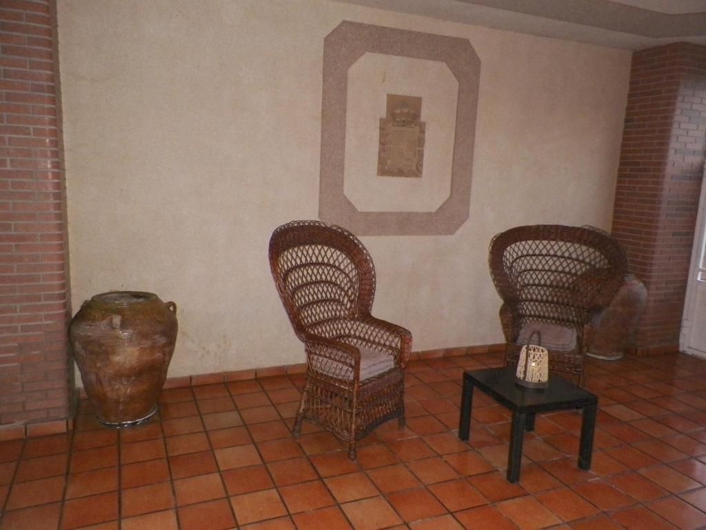 Una habitación con dos sillas de mimbre y una mesa.