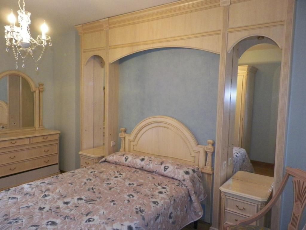 Un dormitorio con una cama, tocador y espejo.