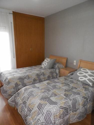 Un dormitorio con dos camas, una mesita de noche y una ventana.