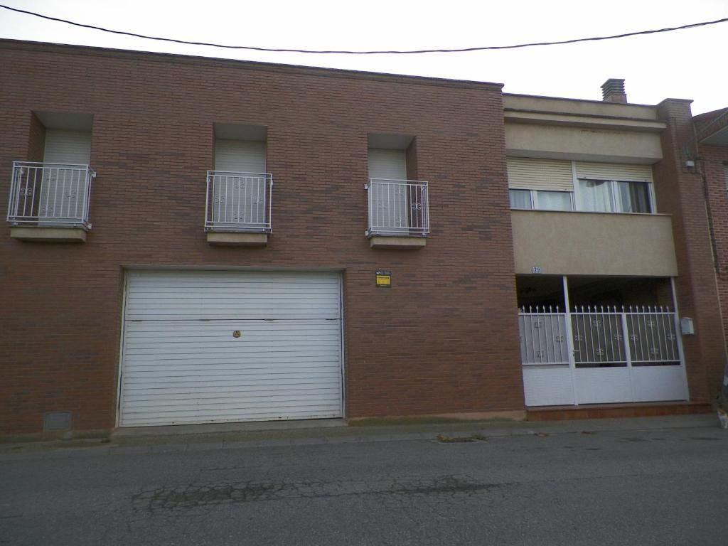 Un edificio de ladrillo con una puerta de garaje blanca y balcones.