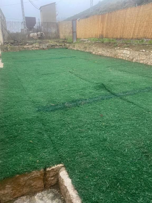 Un patio trasero con mucho césped verde y una valla.