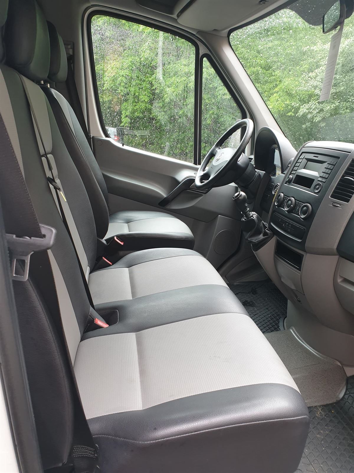 Der Innenraum eines weißen Lieferwagens mit schwarzen und grauen Sitzen