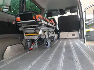 Auf der Ladefläche eines Lieferwagens steht ein Krankenwagen.