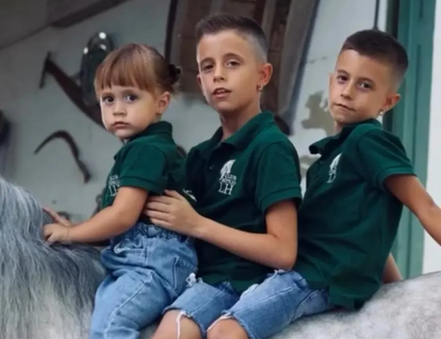 Mujer en un caballo marrón, inclinando la cabeza sobre un camino de tierra, con un sombrero negro, en el campo.