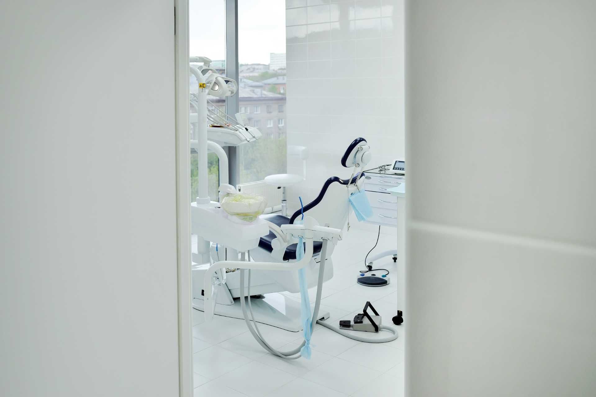 Una silla dental está situada en un consultorio dental al lado de una ventana.