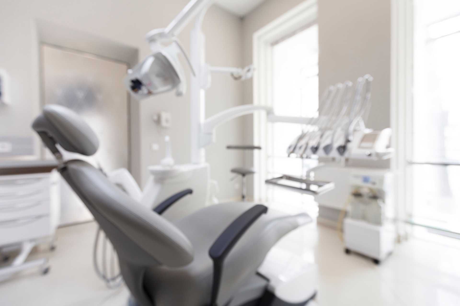 Un consultorio dental vacío con un sillón dental gris.