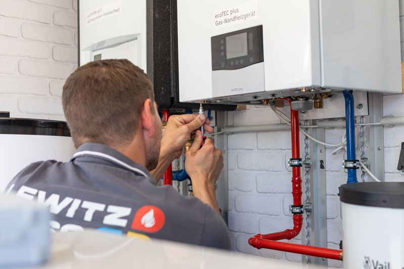 Ein Mann arbeitet an einer Heizungsanlage in einem Raum.