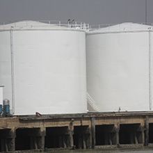 Dois grandes tanques brancos estão posicionados um ao lado do outro em uma doca.