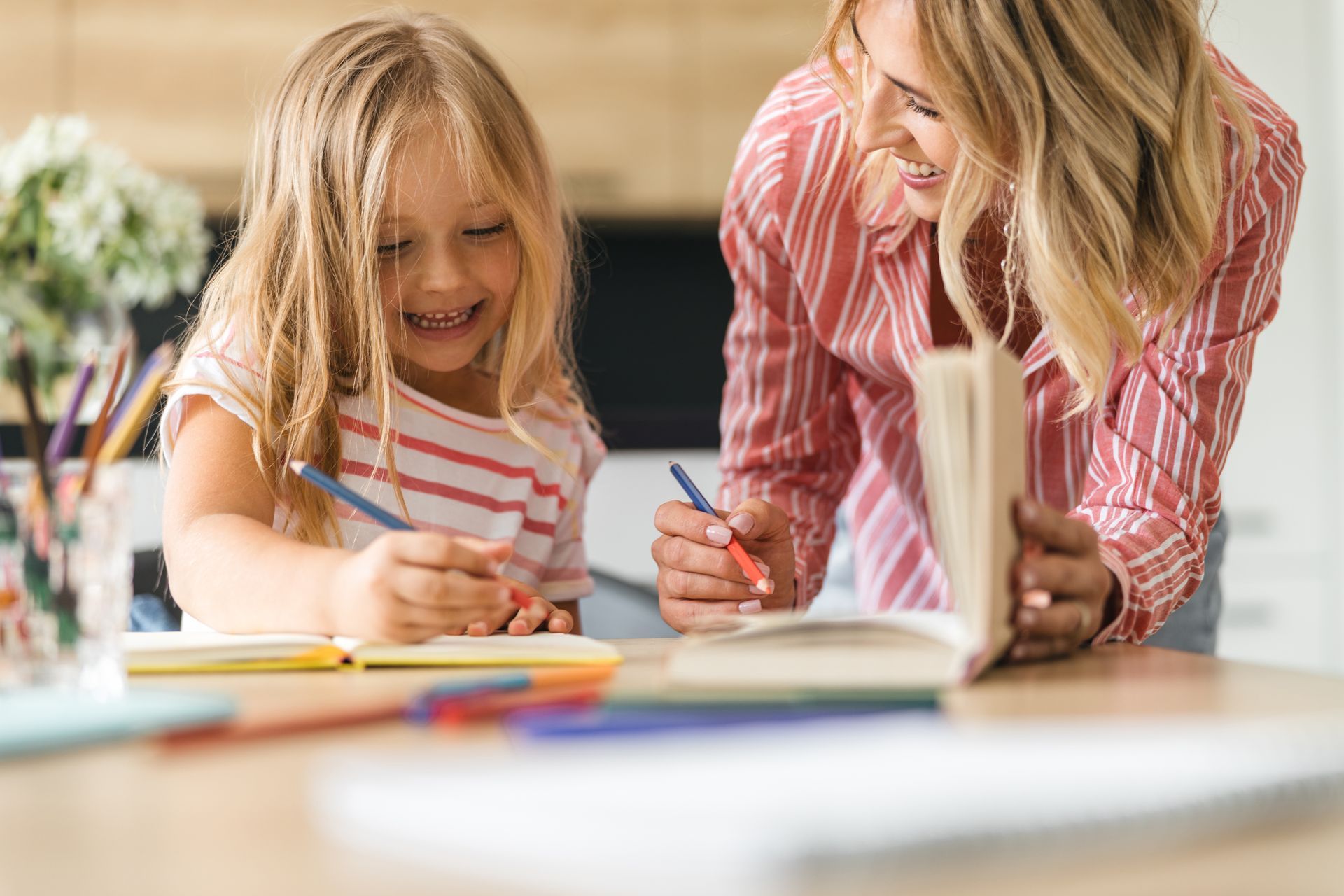 Une femme qui aide une petite fille dans ses devoirs