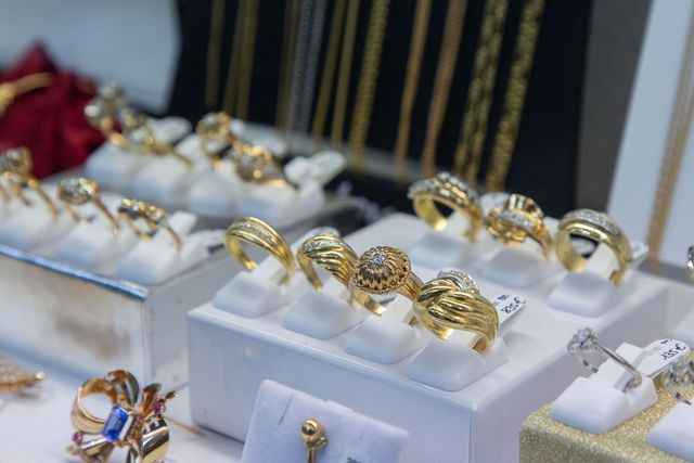 Des bagues en or, certaines serties de diamants, sont exposées dans une bijouterie sur des socles blancs.