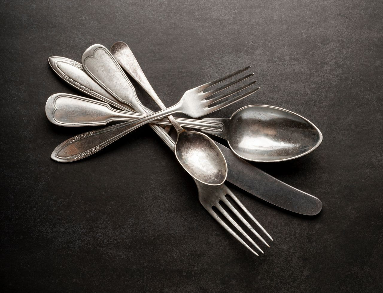 Couverts : plusieurs fourchettes et cuillères sur une surface sombre.