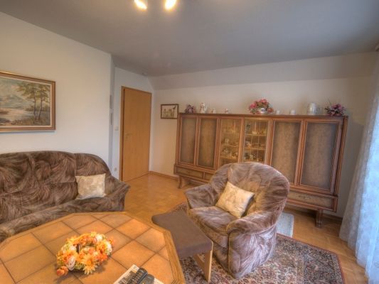 Ein Wohnzimmer mit Couch, Sessel, Tisch und einem Bild an der Wand.