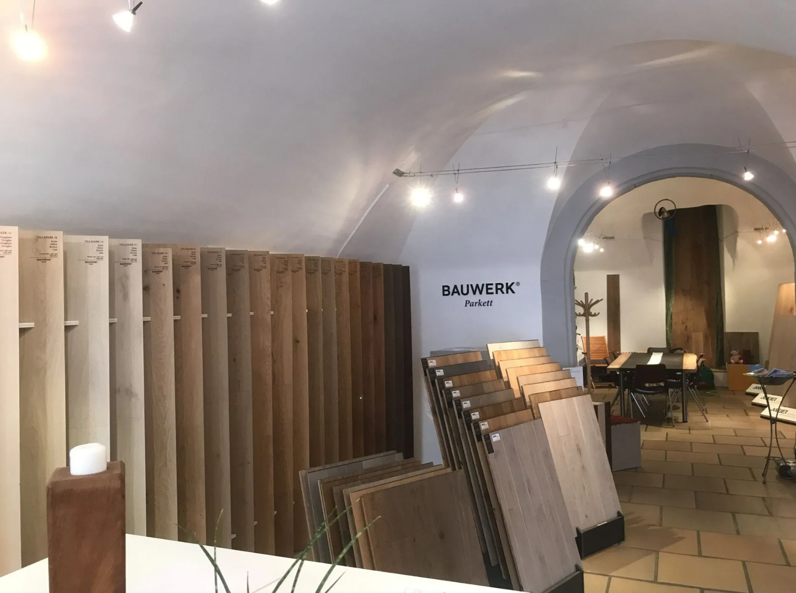Ein Ausstellungsraum mit Reihen verschiedener Holzfussbodendielen, angeordnet in einem gewölbten Raum mit Bogendecke.