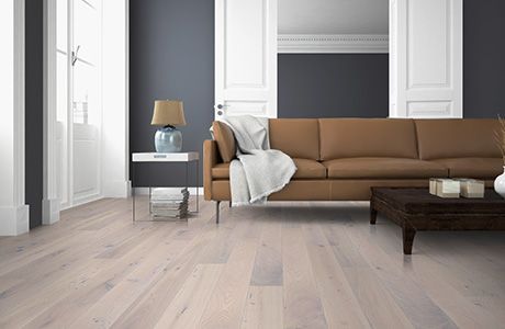 In einem Zimmer mit weissen Türen und dunkelgrauen Wänden steht ein braunes Ledersofa auf hellem Holzboden.