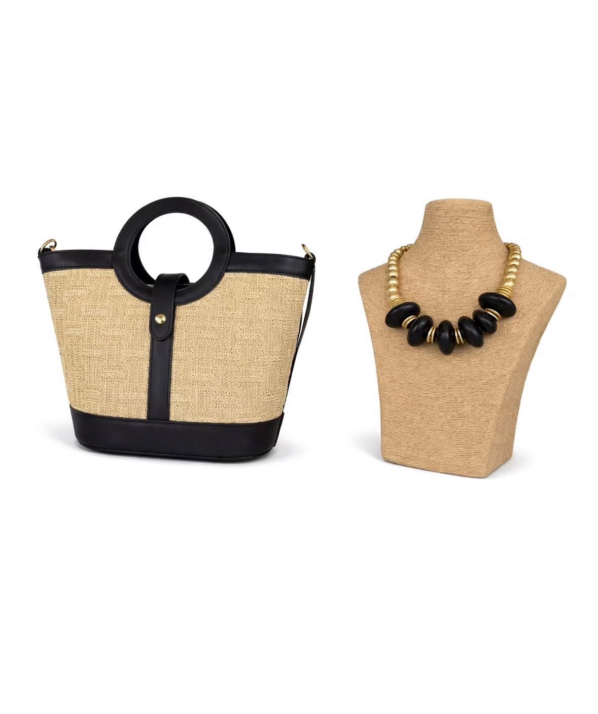 Bolso de paja trenzada y collar de cuentas negras sobre expositores de color beige.