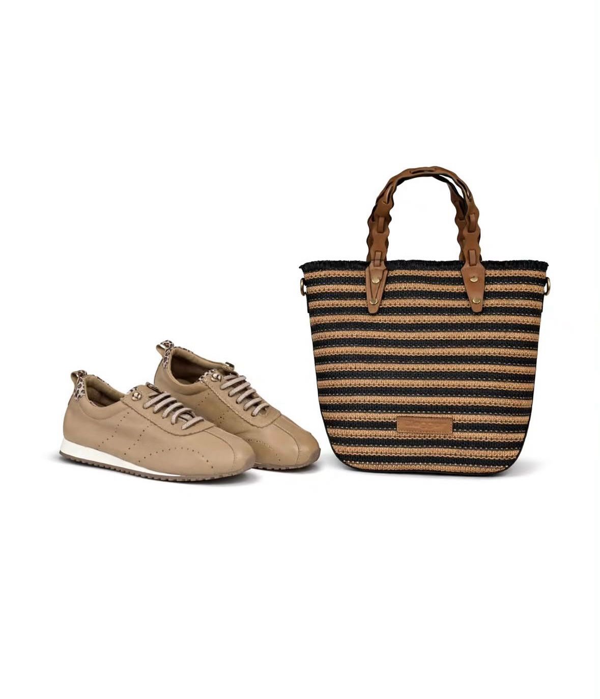 Zapatillas deportivas color canela junto a un bolso de mano tejido a rayas marrones sobre un fondo blanco.