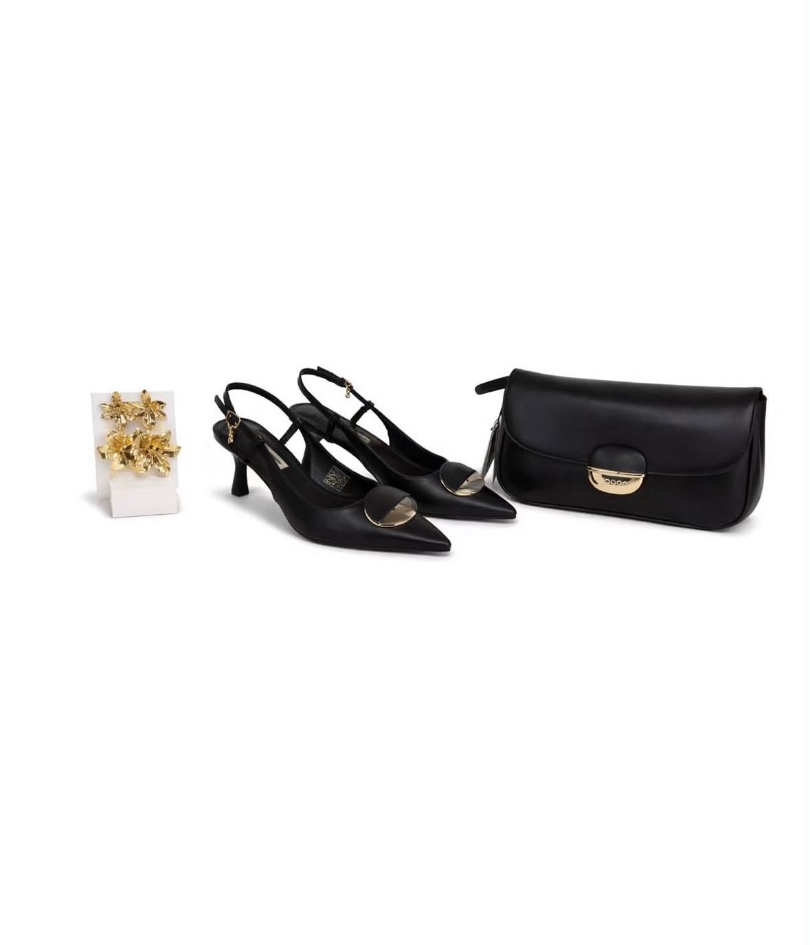 Zapatos de tacón negros con tira trasera, un bolso de mano negro y un pequeño accesorio floral sobre fondo blanco.