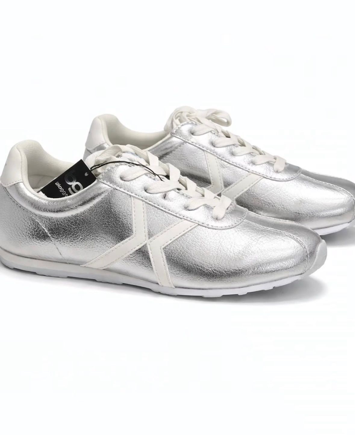 Un par de zapatillas deportivas plateadas con cordones blancos sobre un fondo blanco.