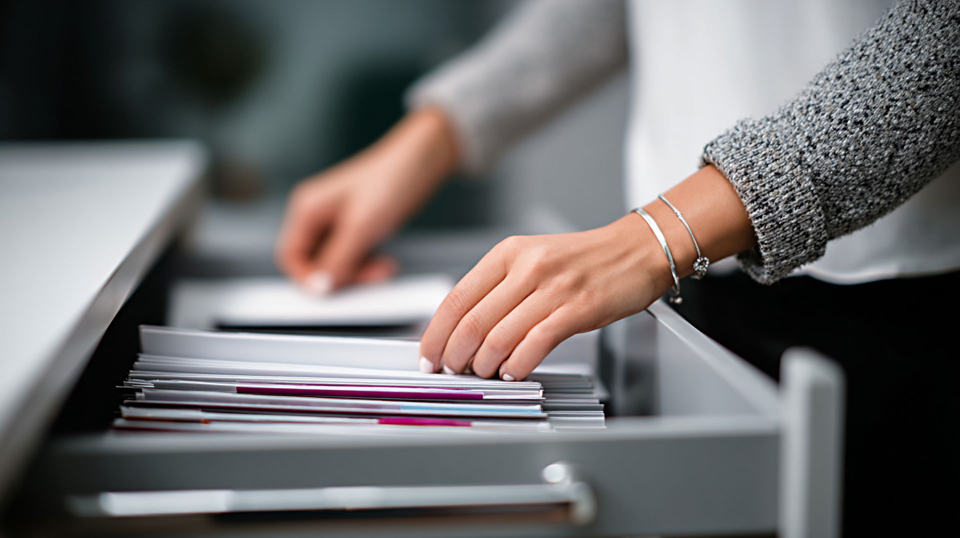 Une personne range des papiers dans un tiroir de bureau.