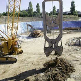 Una grúa está cavando un agujero en el suelo en un sitio de construcción.