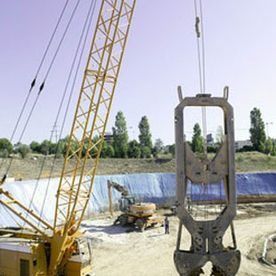 Una gran grúa amarilla está levantando un objeto grande en un sitio de construcción.