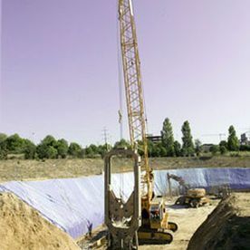 Una gran grúa amarilla está sentada encima de una pila de tierra en un sitio de construcción.