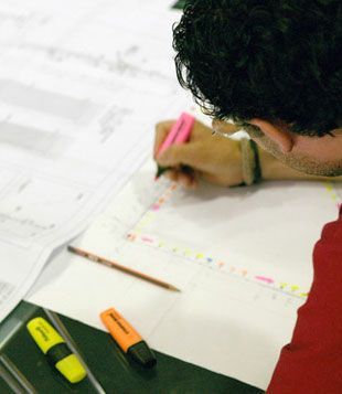 Un hombre está escribiendo en un trozo de papel con un marcador rosa.