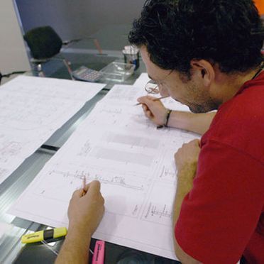 Un hombre con una camisa roja está escribiendo en un trozo de papel.