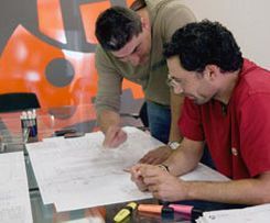 Dos hombres están sentados en una mesa mirando un trozo de papel.