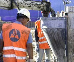 trabajadores de la construcción que llevan chalecos naranjas y cascos de seguridad en un sitio de construcción.