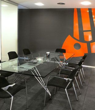 Una sala de conferencias con una mesa de cristal y sillas