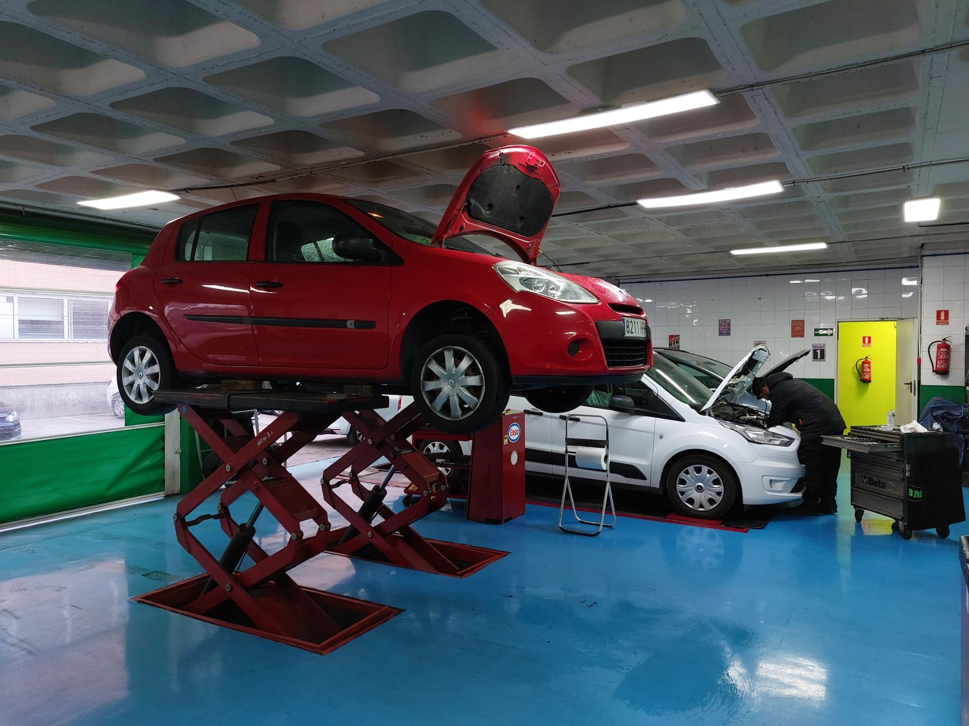 Un coche rojo está estacionado en un elevador en un garaje.