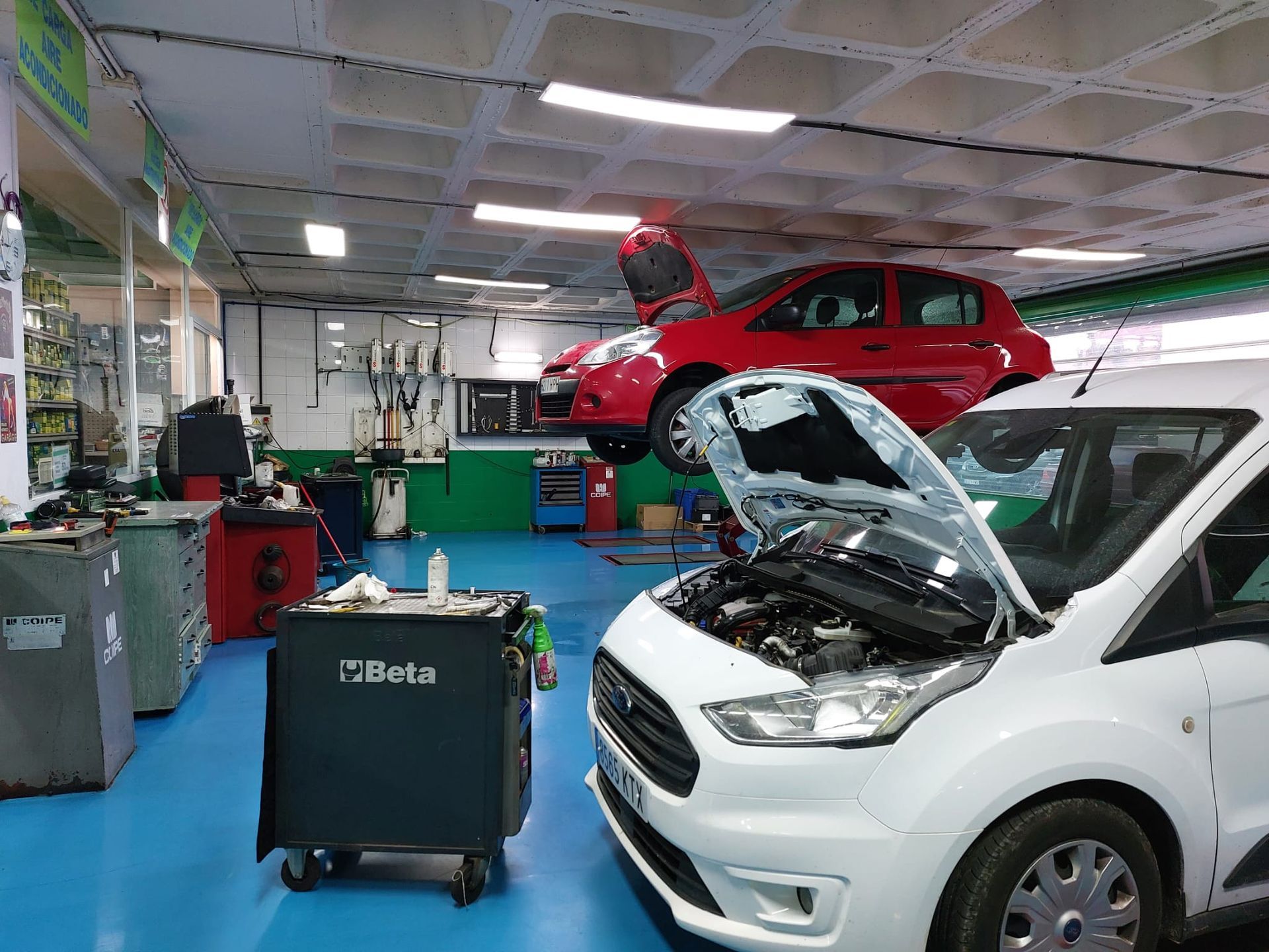 Un coche rojo está sentado encima de una furgoneta blanca en un garaje.