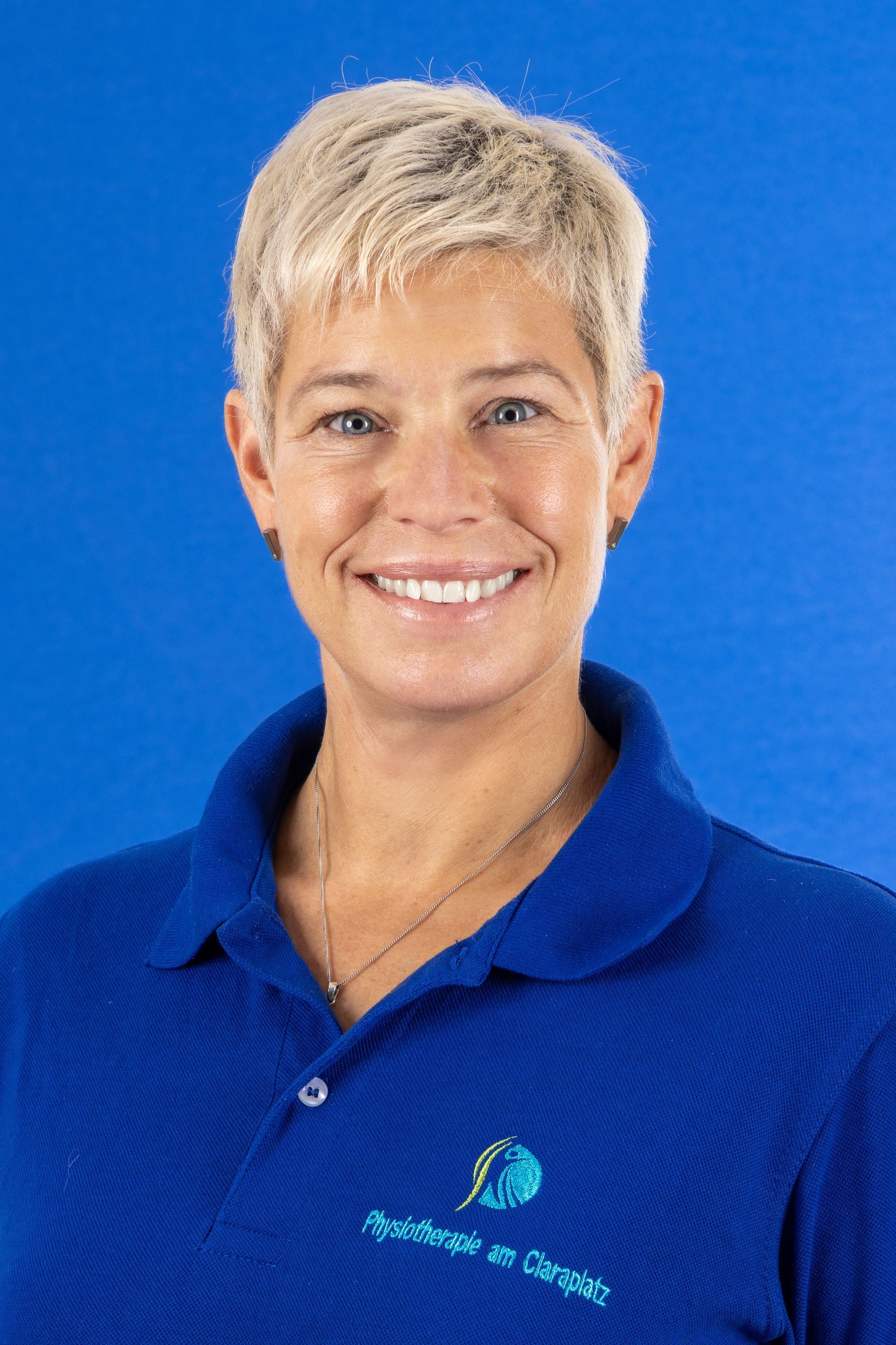 Eine Frau in einem blauen Hemd lächelt in die Kamera.