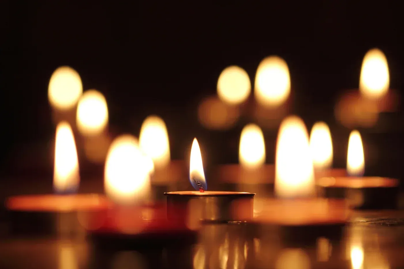 Brennende Kerzen im Dunkeln, sanftes, warmes Leuchten.