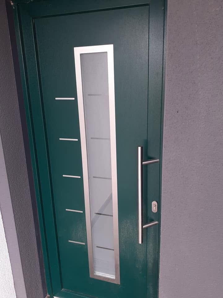 Porte d’entrée verte avec un panneau vertical en verre dépoli et une poignée métallique