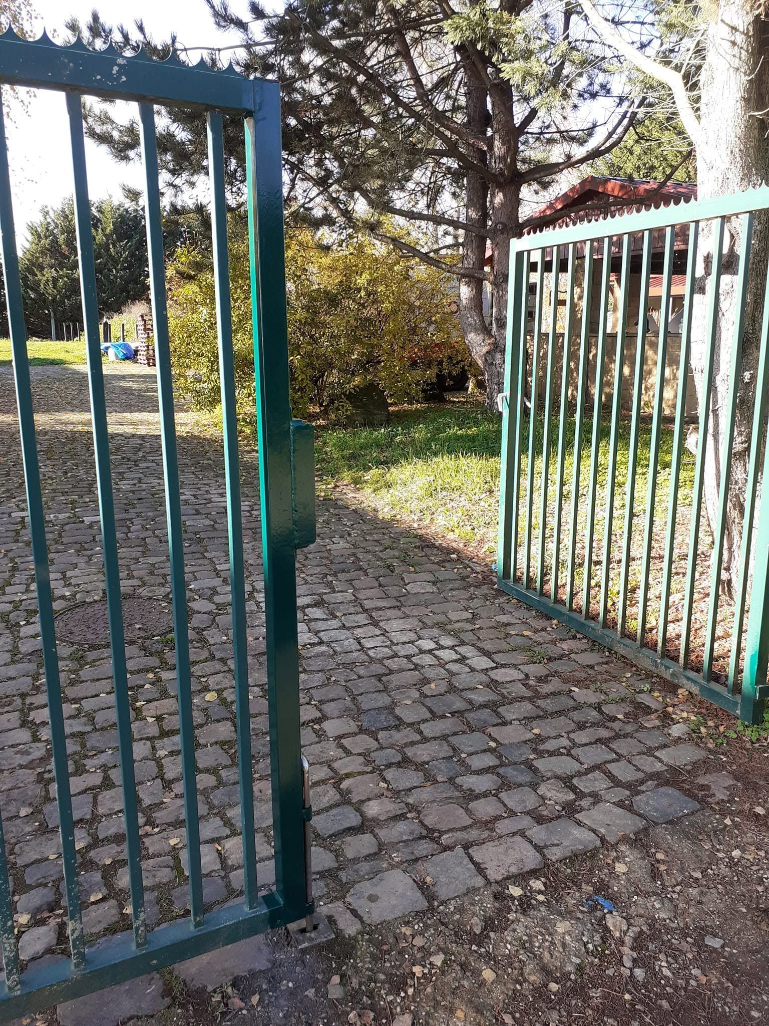 Ouvrez le portail métallique vert qui donne sur une allée pavée dans un jardin ensoleillé