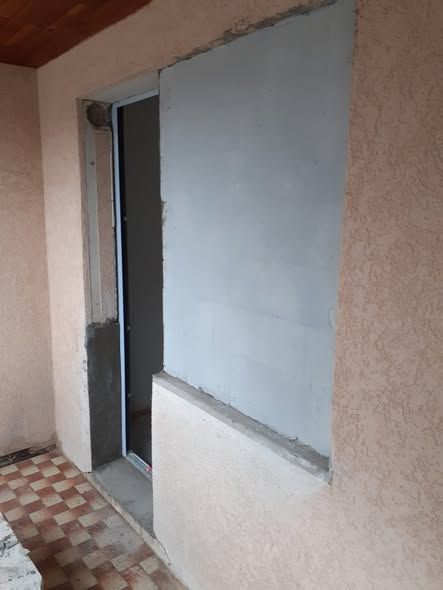 Porte métallique fermée près d’un mur peint en blanc, dans un couloir étroit au sol carrelé à motifs