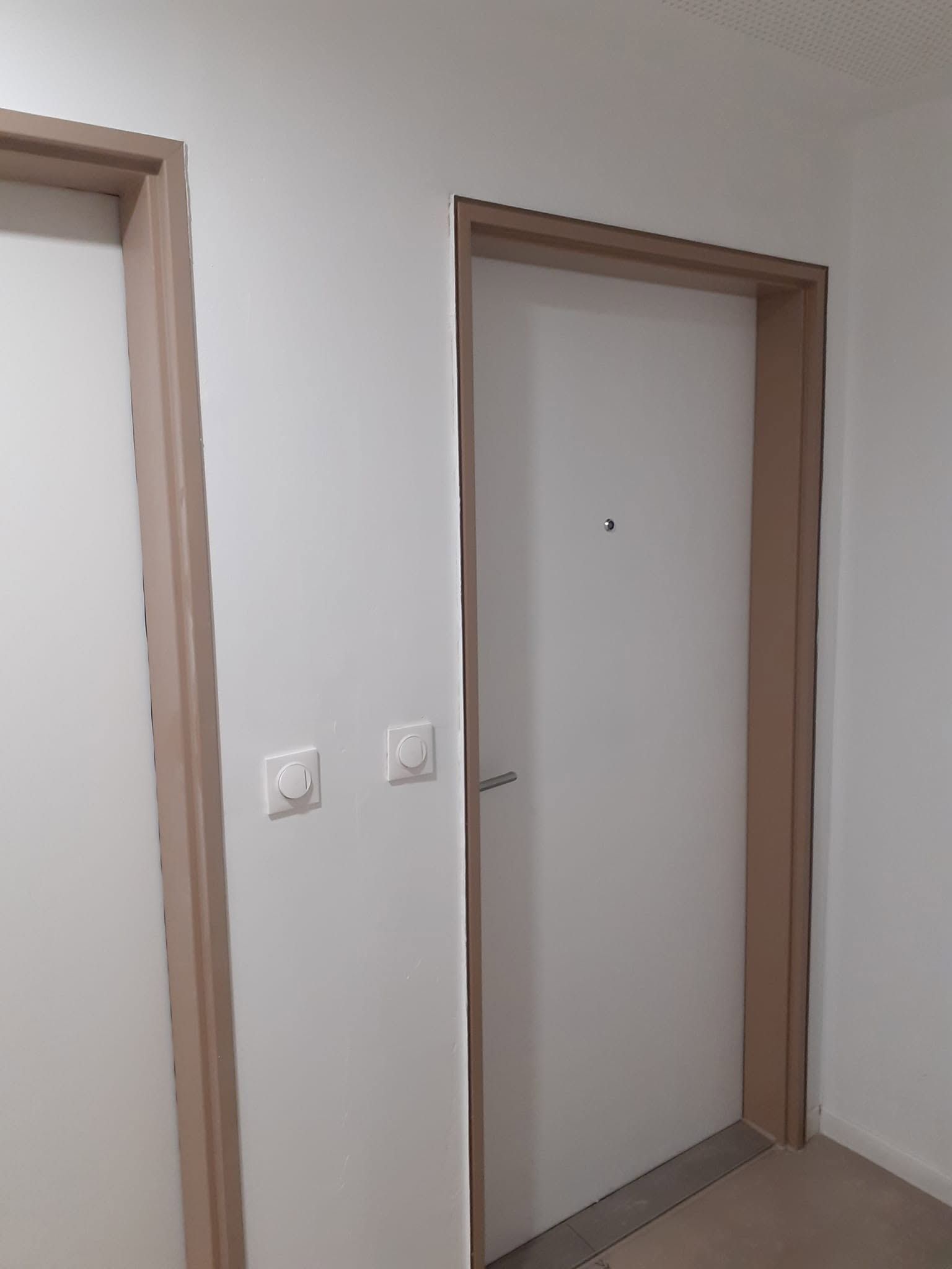 Deux portes intérieures dans un couloir aux murs blancs et aux encadrements en bois clair