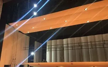 Escenario con luces cenitales, telón curvo y andamios. Brillantes rayos de luz atraviesan la escena.