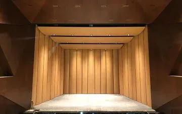 Un pequeño escenario con fondo de paneles de madera, paredes marrones e iluminación cálida.