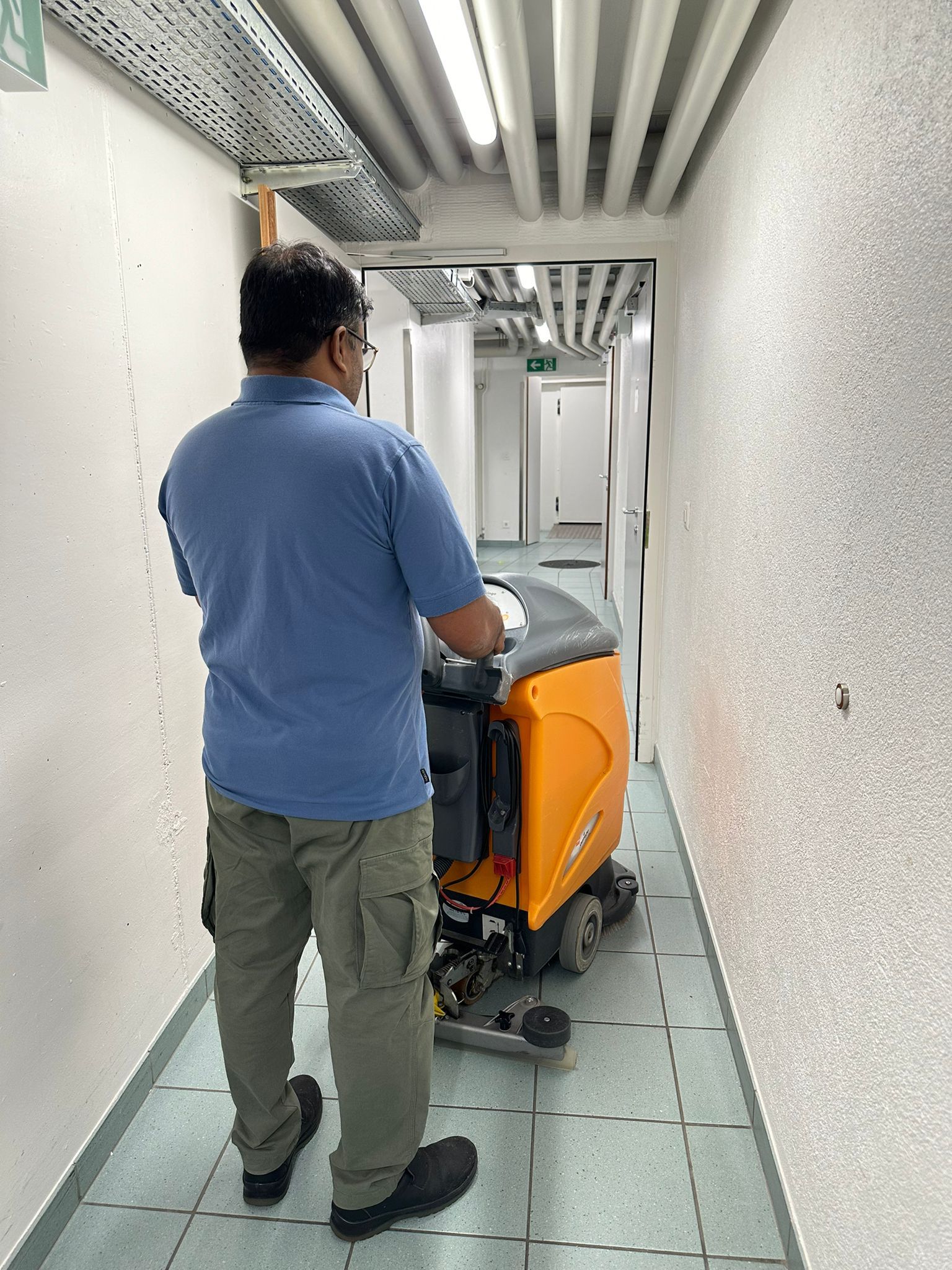 Une femme tient un seau bleu rempli de produits de nettoyage.