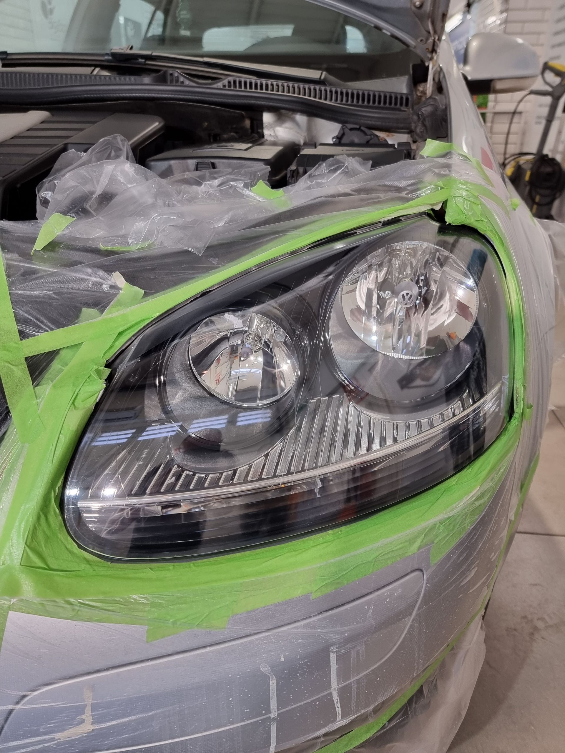 Los faros de un coche están pegados con cinta verde.