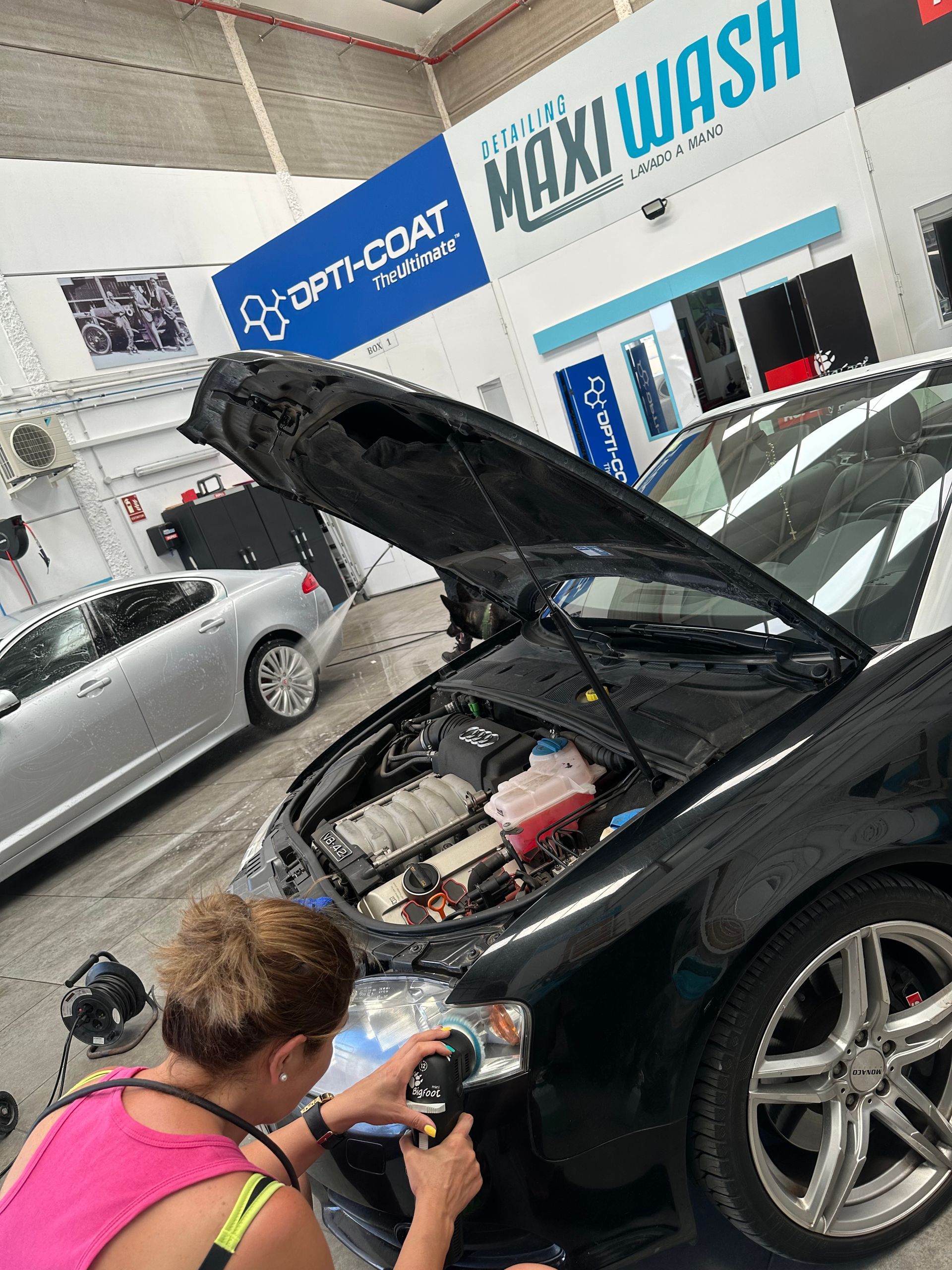 Una mujer está mirando debajo del capó de un coche.