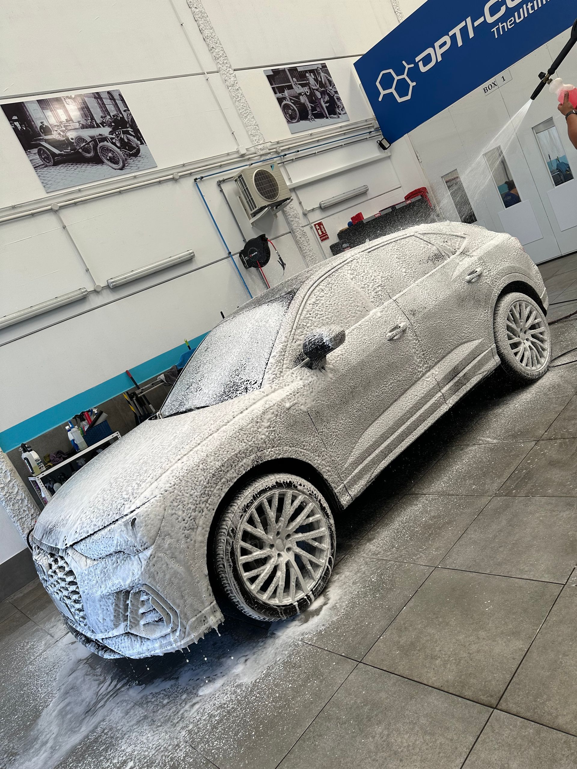 Un coche blanco está cubierto de espuma en un aparcamiento.