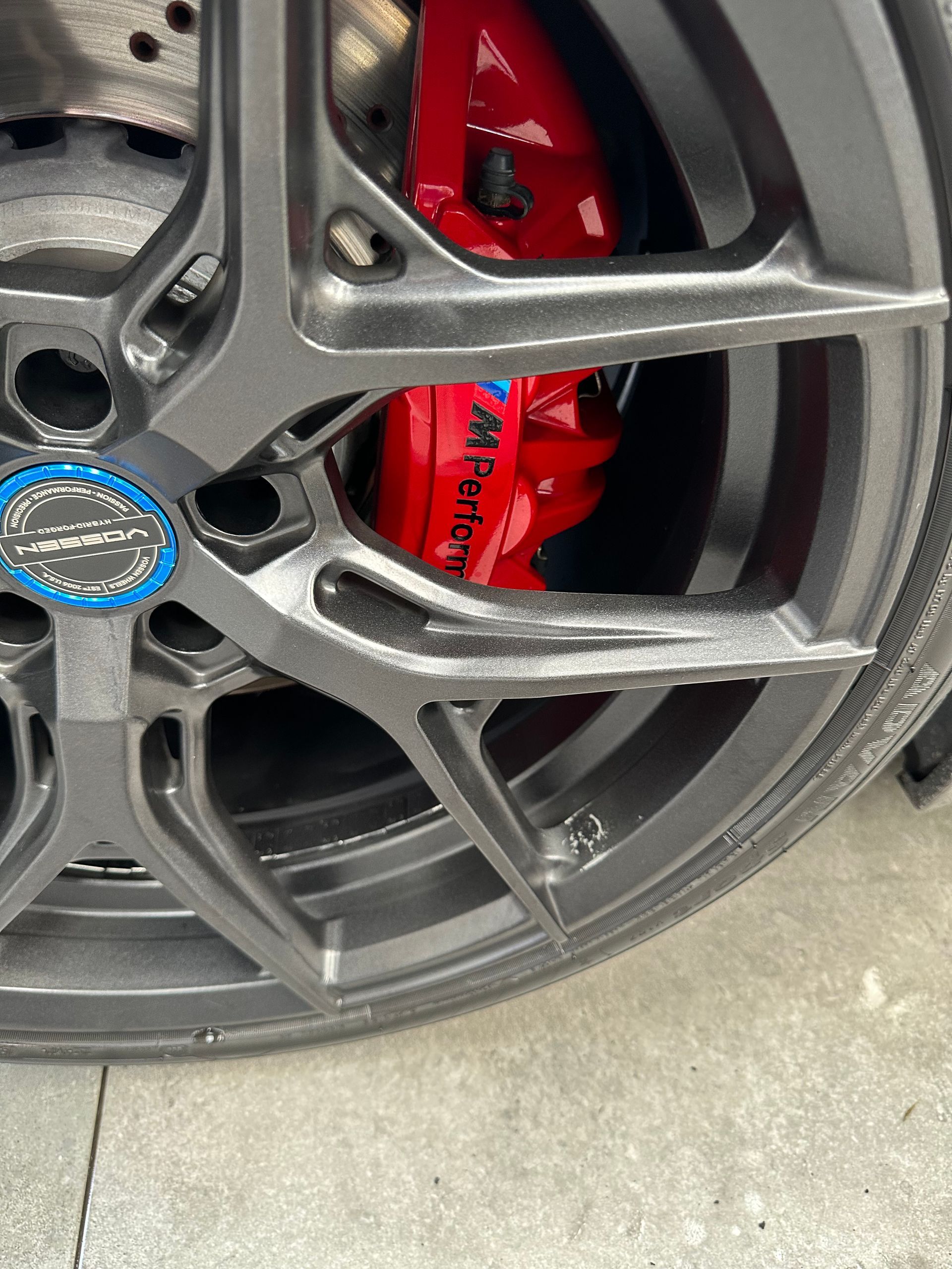 Un primer plano de una rueda de automóvil con una pinza de freno roja.